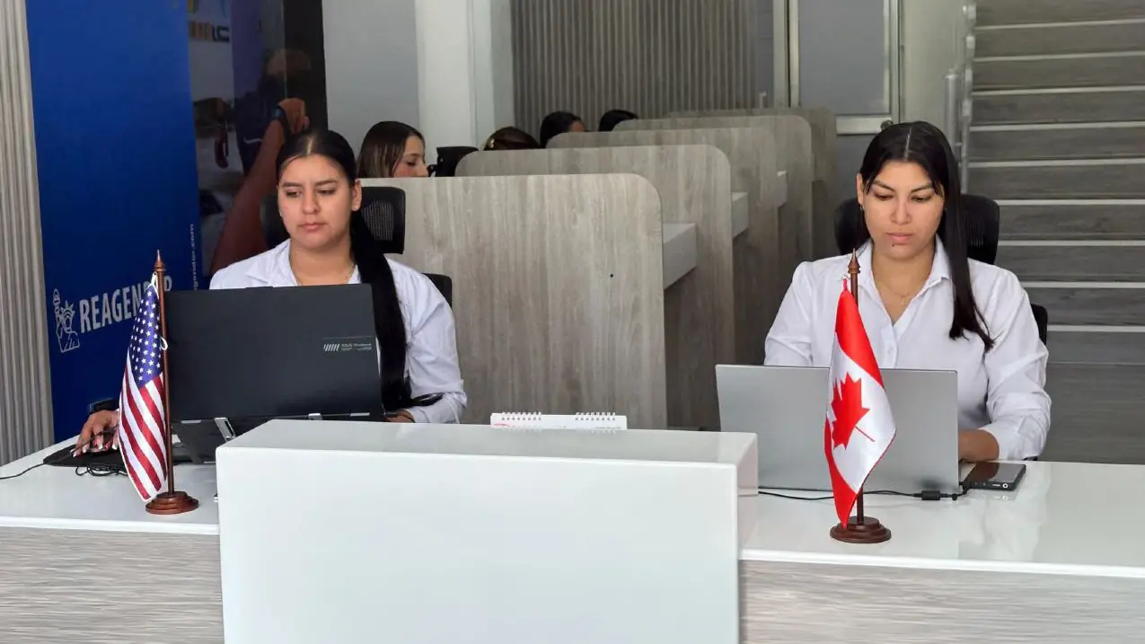 Asesoras de Reagendar trabajando en sus portátiles con las banderas de EE. UU. y Canadá